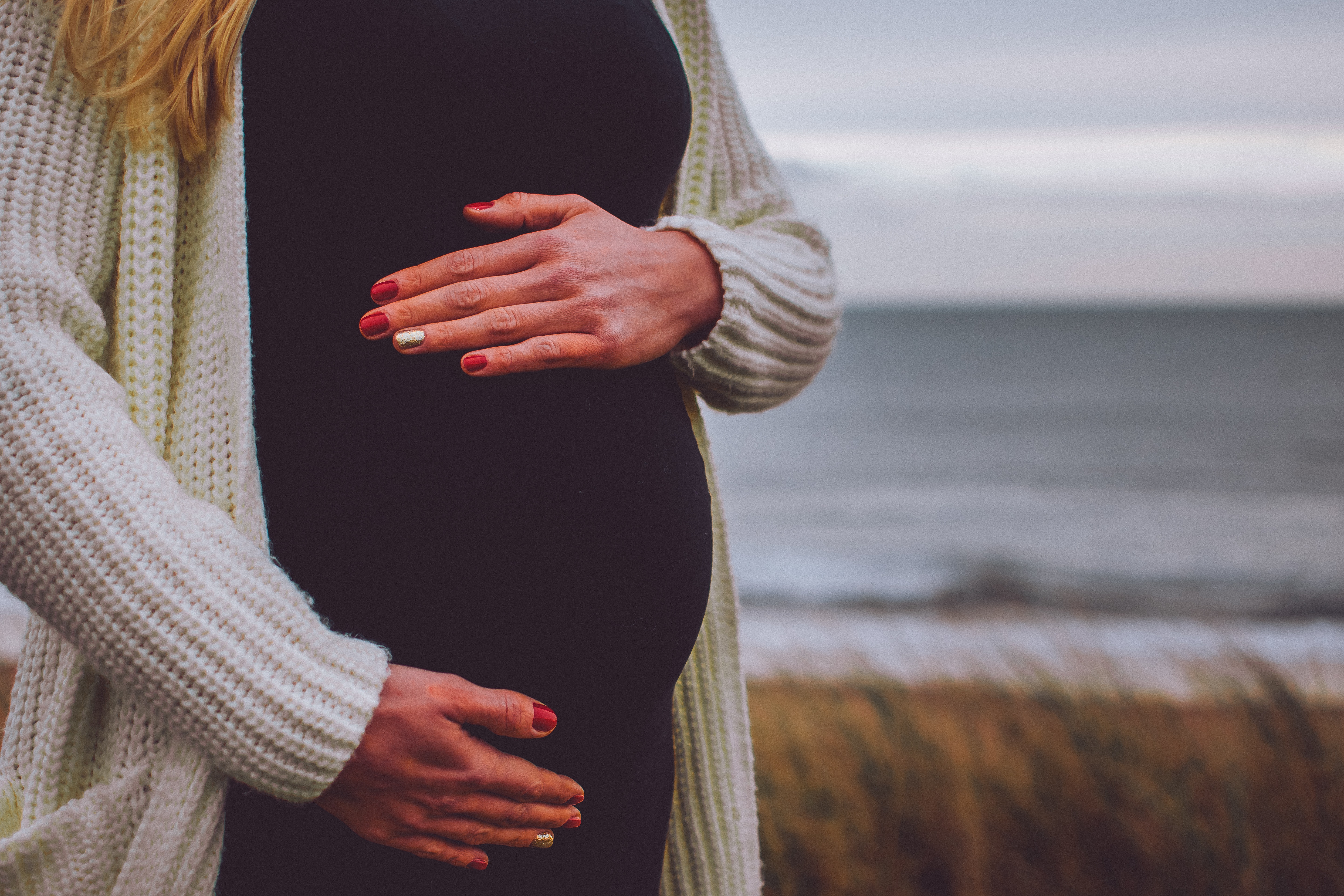 Image of Pregnant Female Holding her Stomach by Ocean