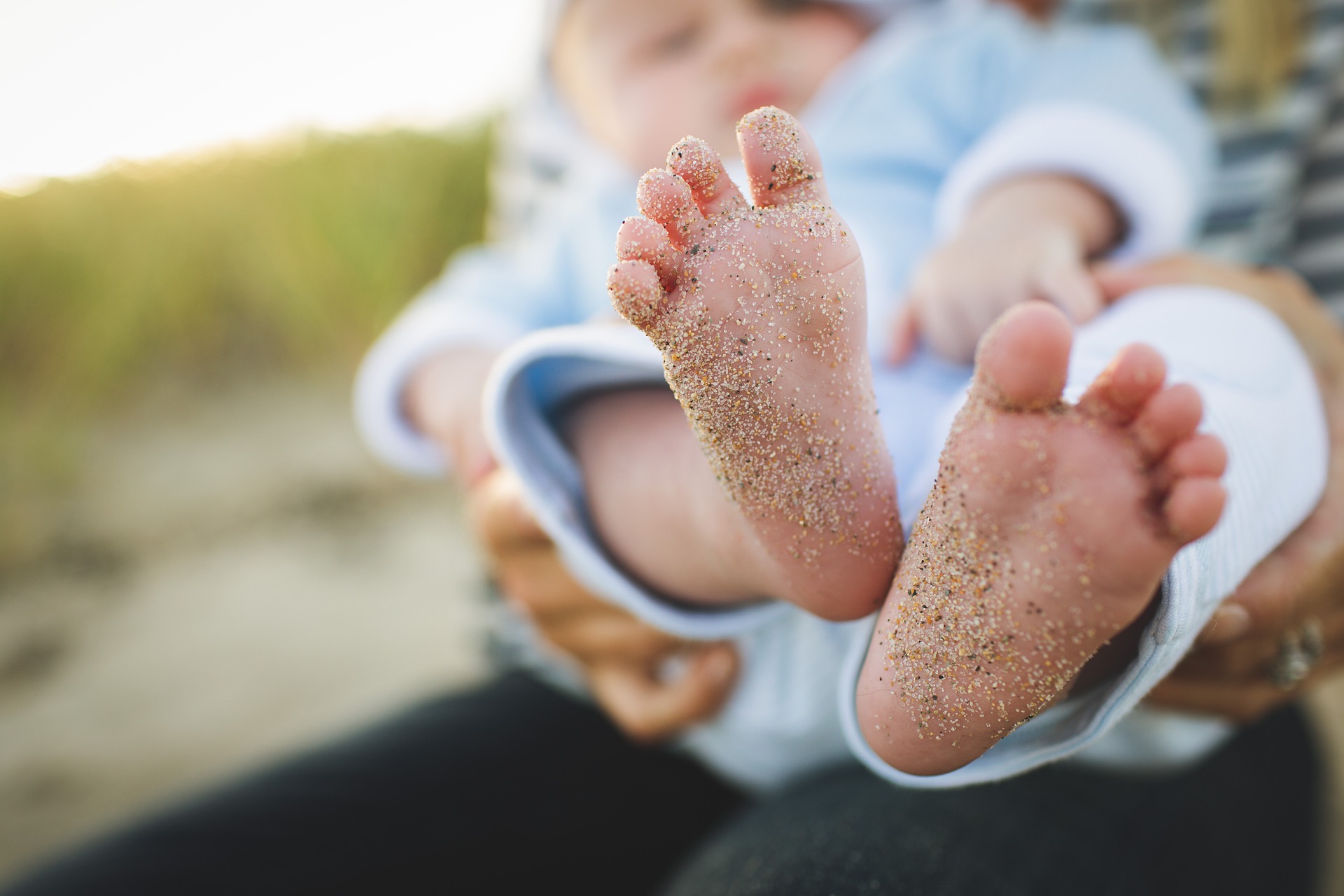 Image of Person Holding Baby with Sand on his feet